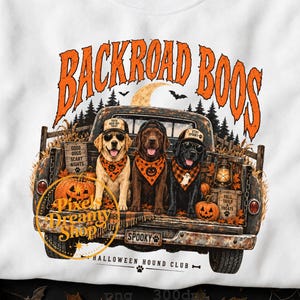 Puede incluir: Una camiseta blanca con un gráfico de tres perros en la parte trasera de una camioneta oxidada. Los perros llevan gorras y pañuelos. El texto dice BACKROAD BOOS, GOOD DOGS SCARY NIGHTS, FALL TAILS & TREATS, SPOOKY y HALLOWEEN HOUND CLUB.