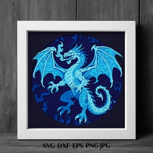 May include: A square white frame containing a circular layered paper art piece featuring a light blue dragon breathing fire against a dark blue background. The dragon has large wings, sharp claws, and a long tail. Text at the bottom reads SVG DXF EPS PNG JPG.