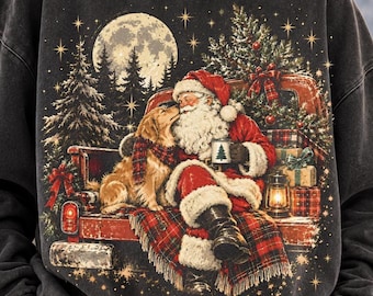 May include: A charcoal gray crewneck sweatshirt featuring a graphic print of Santa Claus sitting in the back of a red pickup truck with a golden retriever, a Christmas tree, wrapped gifts, a lantern, and a full moon in the night sky.