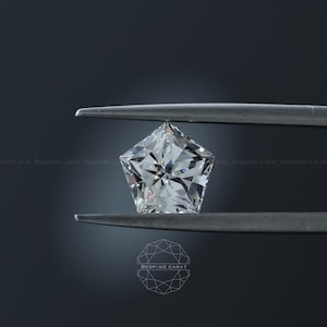 Può includere: Una gemma sfaccettata incolore a forma di pentagono tenuta da una pinzetta di metallo. La pietra presenta un taglio brillante con molteplici sfaccettature triangolari e a forma di aquilone che riflettono la luce. Il testo Bespoke Carat è visibile al centro.