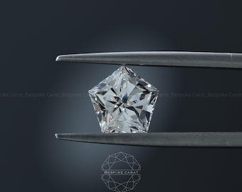 May include: A pentagon-shaped, colorless faceted gemstone held by metal tweezers. The stone features a brilliant cut with multiple triangular and kite-shaped facets that reflect light. The text Bespoke Carat is visible in the lower center.