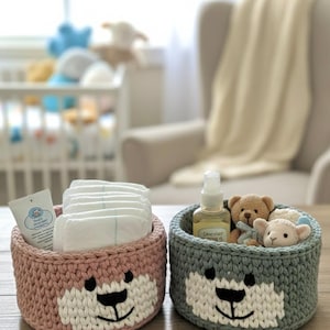 Può includere: Due cestini all'uncinetto fatti a mano, uno rosa e uno grigio, ciascuno con un design a forma di orso. Il cestino rosa contiene pannolini e un tubetto di crema. Il cestino grigio contiene un flacone, orsacchiotti e un giocattolo a forma di agnello. Ideale per una cameretta.