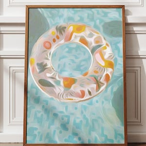 Pode incluir: Uma impressão de arte emoldurada com um design abstrato colorido de uma boia de piscina. A boia é branca com detalhes em laranja, amarelo e rosa, em um fundo de água azul claro. A obra de arte está emoldurada em uma moldura de madeira marrom.