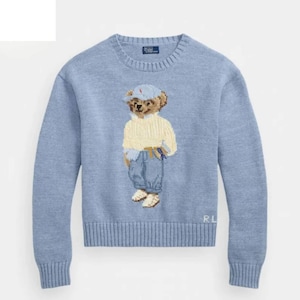 Puede incluir: Suéter azul claro con un oso bordado que lleva un suéter amarillo, vaqueros azules y una gorra azul. El suéter tiene puños y dobladillo acanalados. El logotipo de la marca es visible en la parte superior de la espalda.