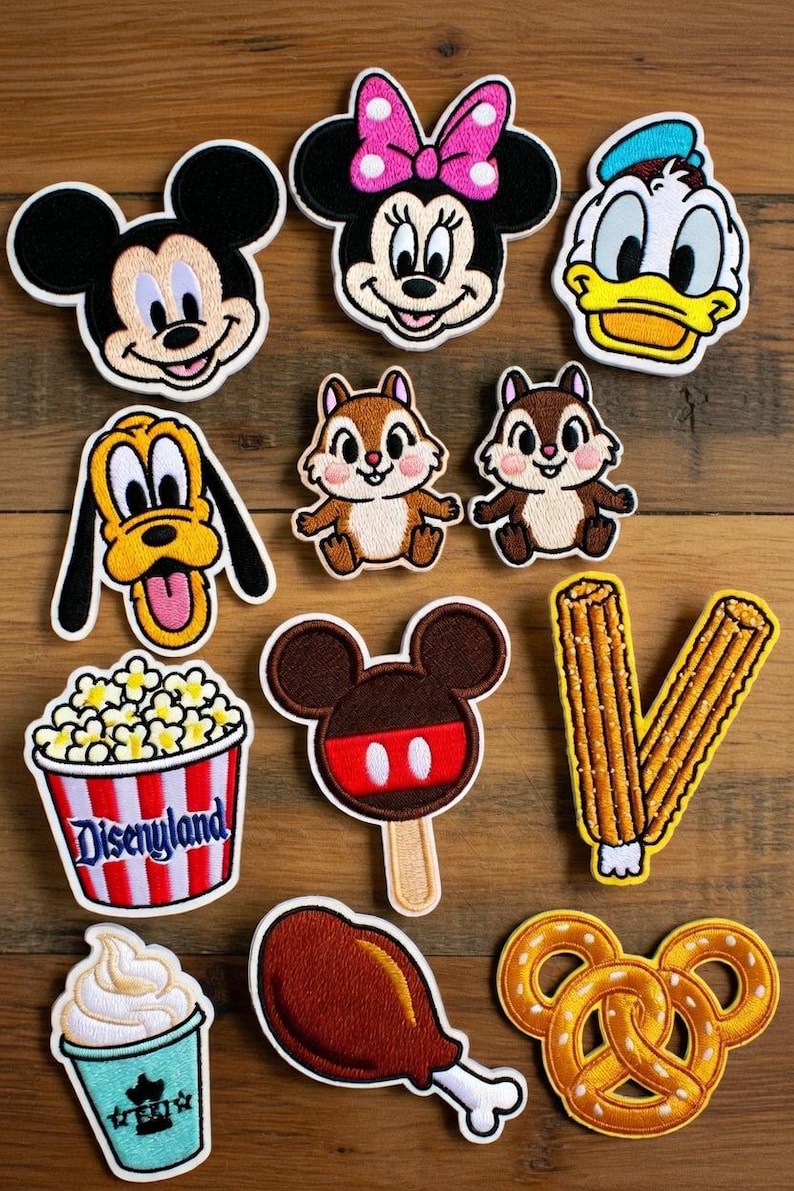 May include: Embroidered patches featuring Disney characters and themed food items. Includes Mickey Mouse, Minnie Mouse, Donald Duck, Pluto, Chip and Dale, popcorn, ice cream, a Mickey-shaped popsicle, churros, a turkey leg, and a Mickey pretzel.
