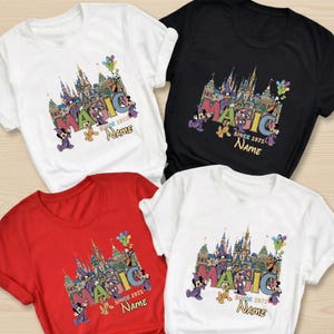 May include: Four t-shirts in white, black, and red, featuring a colorful graphic design. The design includes the word "MAGIC" with a castle illustration, Mickey Mouse, and the text "SINCE 1971" and "Name".