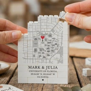 May include: A white, block-style map of the University of Florida with a red heart marking a location. The text "MARK & JULIA" and other details are printed below. A tag with "hand letter studio" is visible.