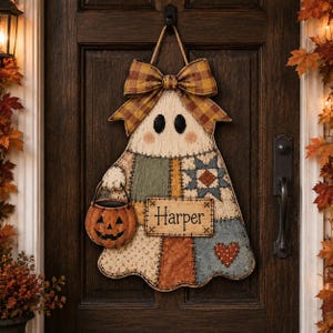 May include: A ghost-shaped door hanger featuring a patchwork design in muted earth tones, topped with a plaid bow. The ghost holds a small orange jack-o'-lantern bucket and displays a rectangular sign with the name Harper printed in black text.