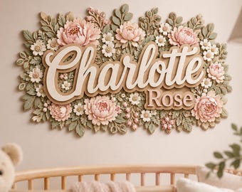 May include: A decorative wall sign featuring the name Charlotte Rose in raised white lettering. The sign is surrounded by a dense arrangement of sculpted pale pink peonies, small white flowers, and sage green leaves in a layered floral design.