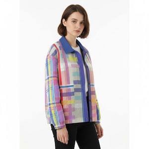 Könnte beinhalten: Eine bunt gemusterte Jacke mit blauem Kragen und Manschetten. Die Jacke zeigt eine lebendige Mischung aus Farben, darunter Rosa, Lila, Gelb und Blau, angeordnet in einem karierten Design. Sie hat zwei Vordertaschen und einen Knopfverschluss.