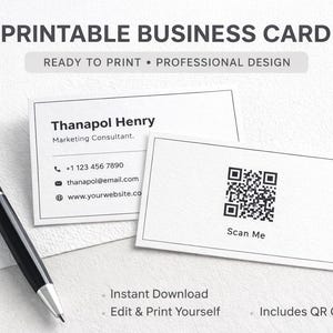 Puede incluir: Un diseño de tarjeta de visita con el texto "PRINTABLE BUSINESS CARD" y "READY TO PRINT • PROFESSIONAL DESIGN". La tarjeta presenta un nombre, información de contacto y un código QR. Un bolígrafo negro está al lado de las tarjetas.