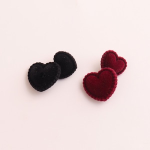 May include: Two pairs of heart-shaped appliques. One pair is black, and the other is a deep burgundy red. The hearts have a stitched edge, giving them a textured appearance. These fabric embellishments are suitable for crafts.
