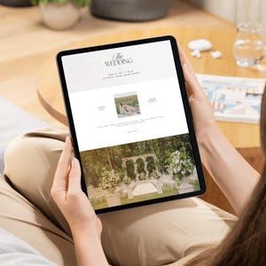 May include: A tablet displaying a digital wedding invitation website. The screen shows the text THE WEDDING, a date, a location, a small square photograph of a couple, and a large image of an outdoor wedding ceremony venue with stone arches.