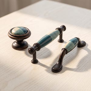 May include: A set of three cabinet hardware pieces including one round knob and two drawer pulls. Each piece features a dark bronze metal finish and a central inlay with a textured, geometric pattern in shades of cream, teal, and dark green.
