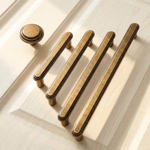 May include: A set of antique brass hardware including one round knob and three elongated drawer pulls. Each piece features a textured, weathered finish with a dark recessed center line and rounded edges, designed for mounting on cabinetry.