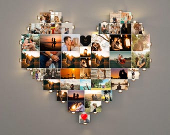 以下が含まれることがあります： 小さな正方形の写真がたくさん集まった、ハート型のフォトコラージュ。各写真は小さなライトで照らされています。写真はカップル、夕日、ロマンチックな瞬間を描いています。コラージュは灰色の壁に取り付けられています。