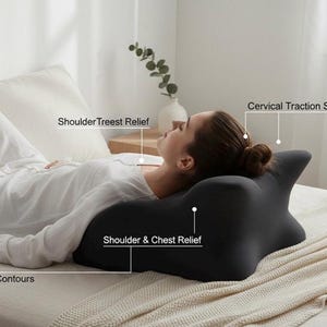 May include: A black ergonomic pillow with a unique shape designed for shoulder and chest relief, cervical traction support, and arm contours. The pillow is shown in a bedroom setting, with a person lying on a bed.
