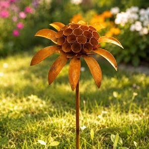 K&ouml;nnte beinhalten: Ein rostfarbener Metall-Gartenstecker in Blumenform. Die Mitte besteht aus einer Ansammlung kleiner, hohler zylindrischer R&ouml;hren, umgeben von einem Kranz aus flachen, spitzen Bl&uuml;tenbl&auml;ttern. Das Ganze wird von einem d&uuml;nnen, geraden Metallstab getragen.