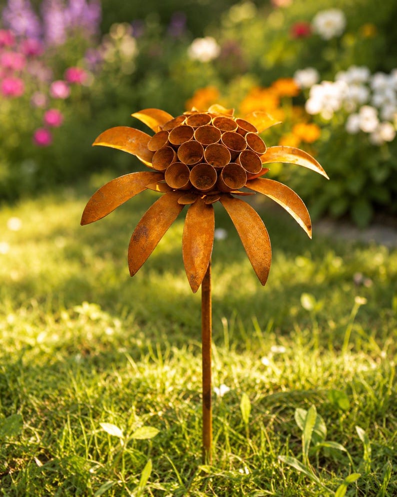 K&ouml;nnte beinhalten: Ein rostfarbener Metall-Gartenstecker in Blumenform. Die Mitte besteht aus einer Ansammlung kleiner, hohler zylindrischer R&ouml;hren, umgeben von einem Kranz aus flachen, spitzen Bl&uuml;tenbl&auml;ttern. Das Ganze wird von einem d&uuml;nnen, geraden Metallstab getragen.