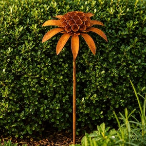 K&ouml;nnte beinhalten: Ein rostfarbener Gartenstecker aus Metall in Form einer Blume. Der Bl&uuml;tenkopf besteht aus einer zentralen Ansammlung kleiner, kreisf&ouml;rmiger, hohler R&ouml;hren, die von einem Kranz aus langen, spitzen Bl&uuml;tenbl&auml;ttern umgeben sind. Ein d&uuml;nner, gerader Stab.