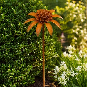 K&ouml;nnte beinhalten: Ein rostfarbener Gartenstecker aus Metall in Blumenform. Die Bl&uuml;te besteht aus einem zentralen B&uuml;ndel kleiner, hohler zylindrischer R&ouml;hren, umgeben von einer Reihe langer, spitzer Bl&uuml;tenbl&auml;tter. Das Ganze wird von einem d&uuml;nnen Metallstab getragen.