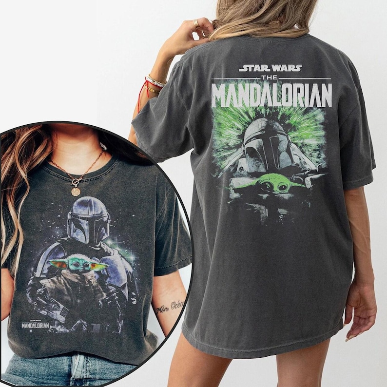Puede incluir: Camiseta gris oscuro con un gr&aacute;fico de The Mandalorian y Grogu de Star Wars. La parte delantera muestra los personajes, mientras que la trasera muestra el t&iacute;tulo de la serie y una figura con casco. La camiseta tiene un aspecto vintage.