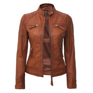 May include: A brown leather jacket with a stand-up collar and a front zipper closure. The jacket has two zippered chest pockets and two side pockets. The shoulders have quilted detailing. The jacket is a classic style.