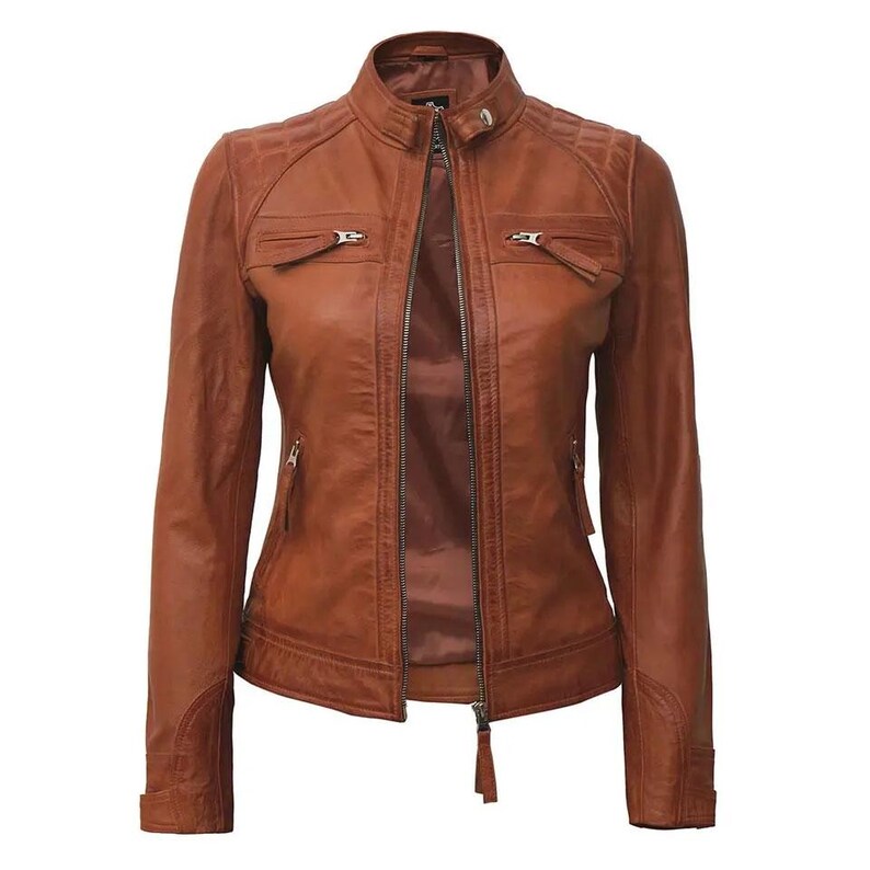 May include: A brown leather jacket with a stand-up collar and a front zipper closure. The jacket has two zippered chest pockets and two side pockets. The shoulders have quilted detailing. The jacket is a classic style.