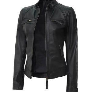 May include: A black leather jacket with a quilted shoulder design, a stand-up collar, and multiple zippered pockets. The jacket has a full-length zipper closure and a tailored fit. The sleeves have zippered cuffs. A classic outerwear piece.