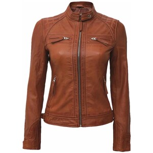 May include: A brown leather jacket with a zip-up front, two chest pockets, and two side pockets. The jacket has a quilted design on the shoulders and a stand-up collar. The jacket is a classic style.