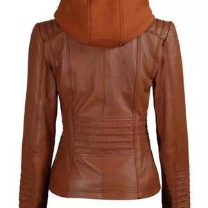 May include: A brown leather jacket with a hood. The jacket has a fitted silhouette with a series of horizontal pleats across the lower back. The sleeves have a ribbed design on the lower portion. The hood is a darker shade of brown.