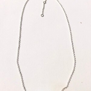 May include: A silver chain necklace with a row of light blue glass beads.