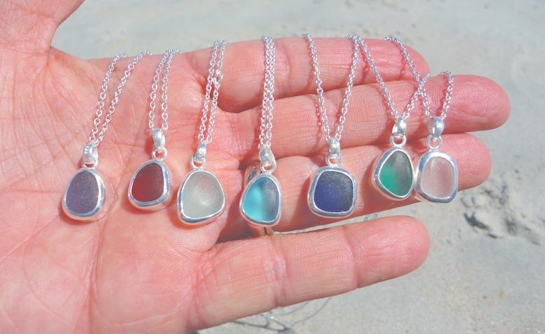 May include: Seven silver necklaces with different colored sea glass pendants. The pendants are all in the shape of a teardrop and are set in silver.