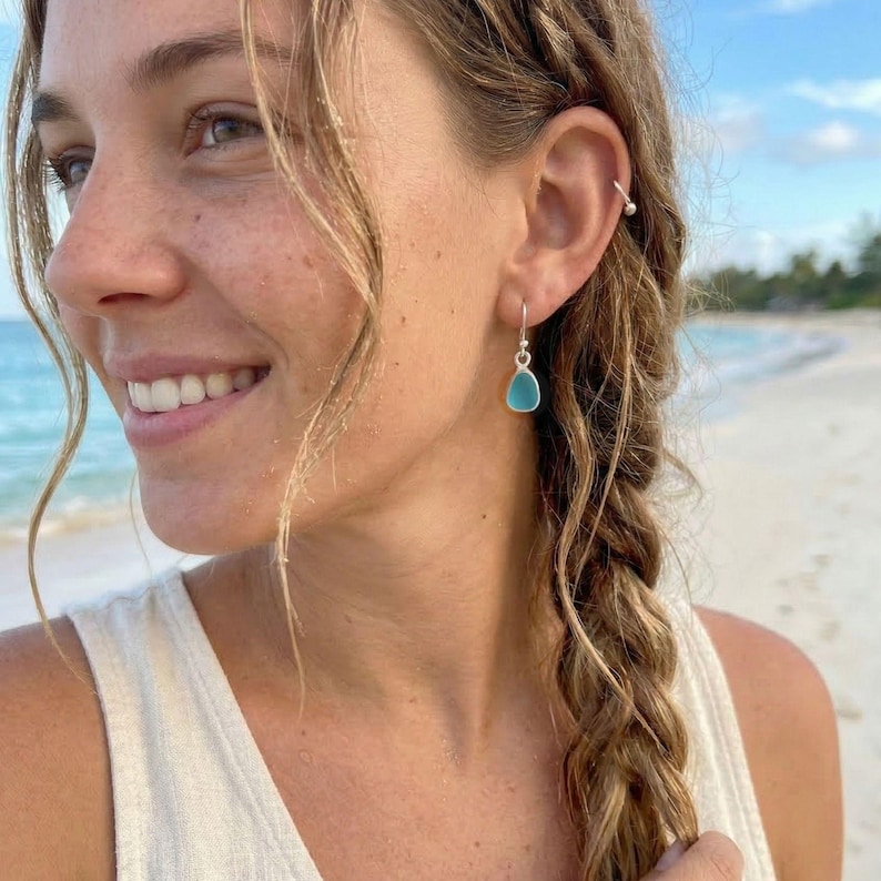 May include: Teardrop-shaped turquoise earrings with silver hooks. The earrings are a vibrant blue-green color and hang from the ear. The earrings are a simple, elegant design, perfect for everyday wear. The earrings are a great addition to any jewelry collection.