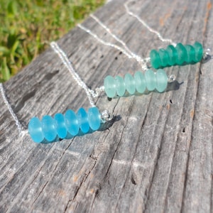 May include: Three silver necklaces with graduated sea glass beads. The necklaces feature different shades of blue and green sea glass beads.