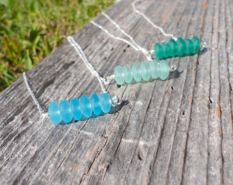 May include: Three silver necklaces with graduated sea glass beads. The necklaces feature different shades of blue and green sea glass beads.