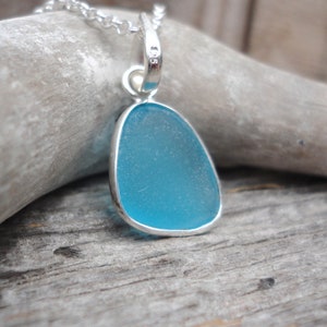 Op de afbeelding: Een zilveren ketting met een hanger met een lichtblauw stuk zeeglas.