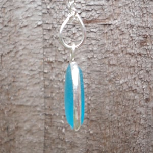 Op de afbeelding: Een zilveren ketting met een hanger gemaakt van een lichtblauw stuk zeeglas.