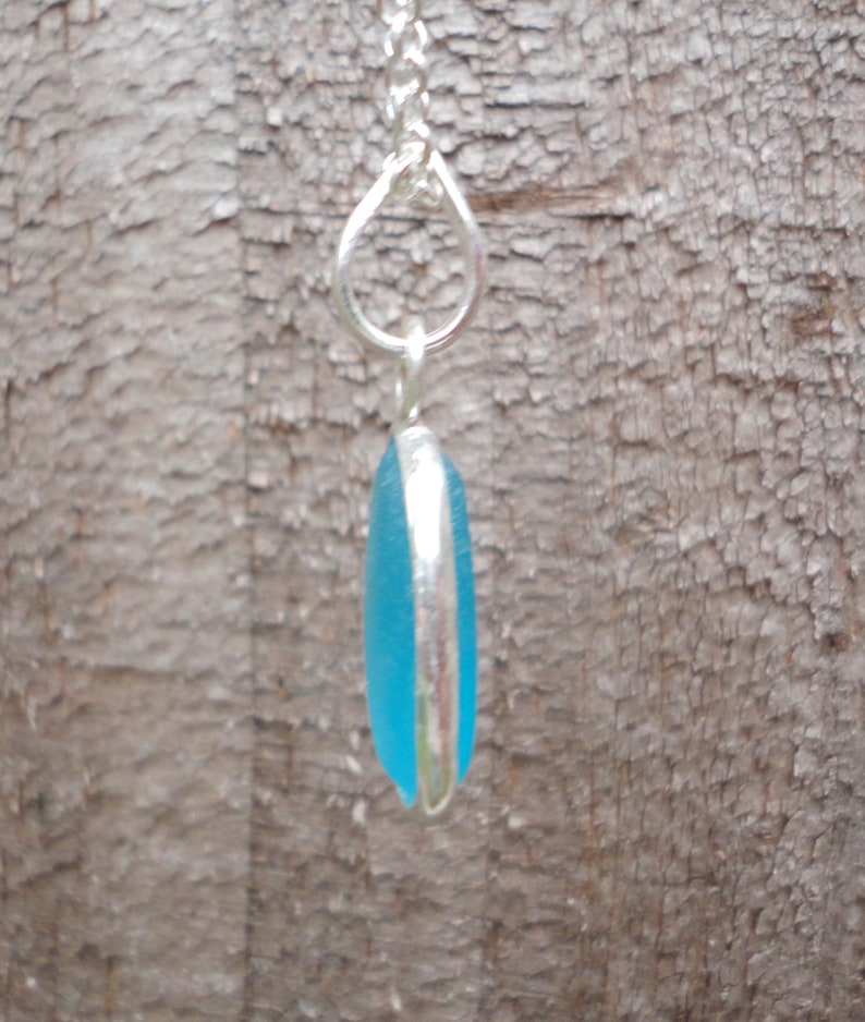 Op de afbeelding: Een zilveren ketting met een hanger gemaakt van een lichtblauw stuk zeeglas.