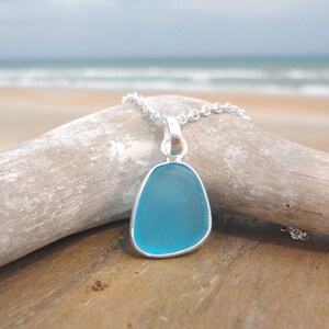 Op de afbeelding: Een ketting met een turquoise zeeglas hanger aan een zilveren ketting. De hanger heeft de vorm van een traan en is gezet in een zilveren bezel.