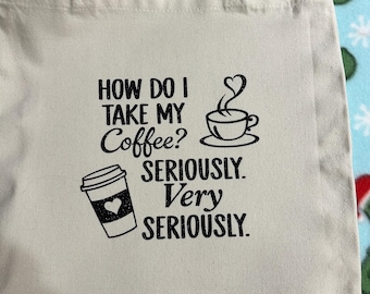 May include: Beige tote bag with black text and graphics. The text reads "HOW DO I TAKE MY Coffee? SERIOUSLY. Very SERIOUSLY." A coffee cup with steam shaped like a heart and a to-go coffee cup are also printed on the bag.