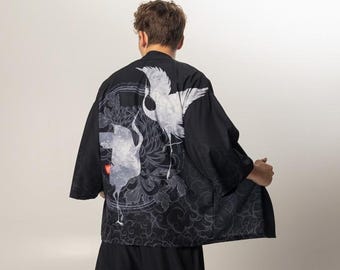 May include: Black kimono-style jacket and matching pants. The jacket features a white crane design on the back. The pants have a decorative pattern at the hem. The outfit is worn with white sneakers.