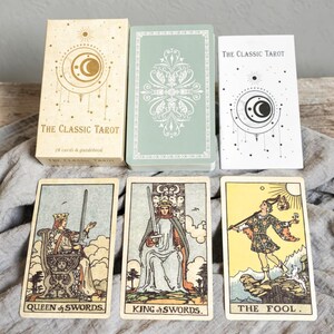 Rider Waite tarot cards Queen of Swords, King of Swords and The Fool displayed with Classic Tarot box and guidebook