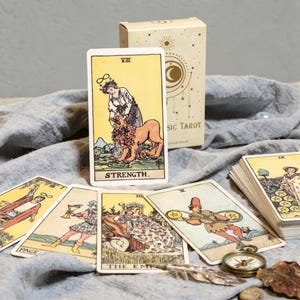 Strength tarot card from Classic Rider Waite tarot deck with tarot box, vintage compass and spiritual accessories