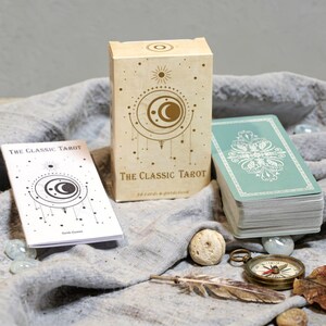 Classic Tarot deck box with crescent moon design, Rider Waite tarot cards, English guidebook and stacked tarot deck on neutral fabric background