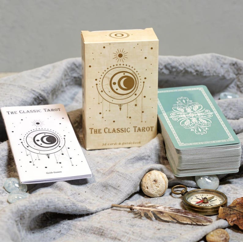 Classic Tarot deck box with crescent moon design, Rider Waite tarot cards, English guidebook and stacked tarot deck on neutral fabric background