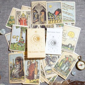 Complete Rider Waite tarot deck spread with Classic Tarot box, English guidebook and traditional tarot illustrations on cloth background