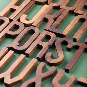 May include: A handmade wooden sign with the text "Welcome" in a playful font. The sign is painted white with a distressed finish, and features a decorative floral design in shades of pink and green. It measures approximately 12 inches wide.