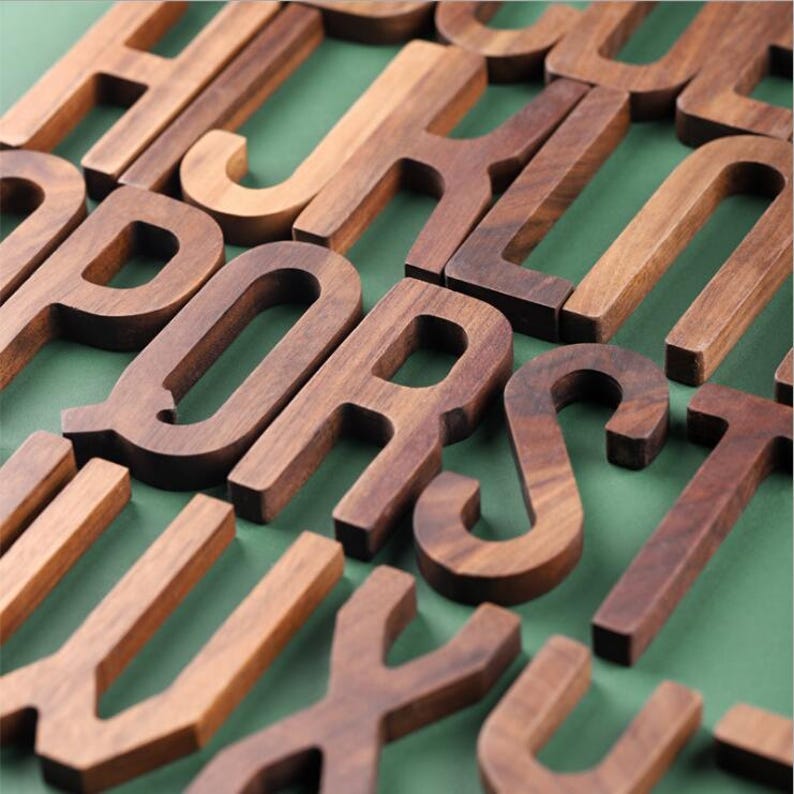 May include: A handmade wooden sign with the text "Welcome" in a playful font. The sign is painted white with a distressed finish, and features a decorative floral design in shades of pink and green. It measures approximately 12 inches wide.