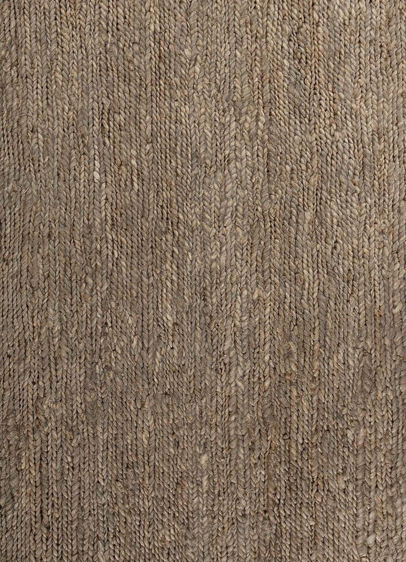 May include: Close-up of a woven rug with a natural, earthy aesthetic. The rug features a textured surface with a repeating pattern of vertical braids in varying shades of brown and tan. This rug is suitable for home decor.
